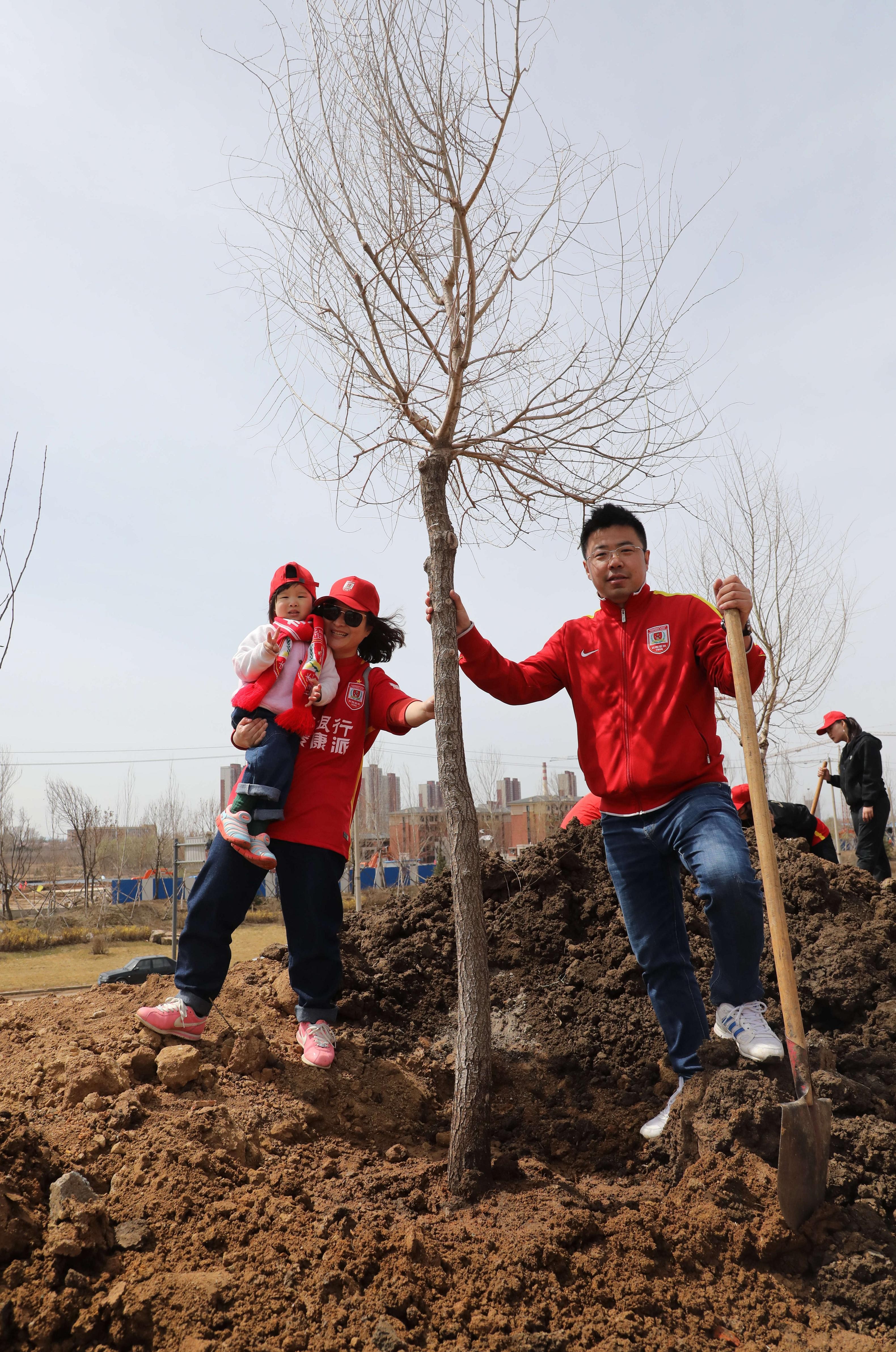一家三口在亲手栽种的小树前合影